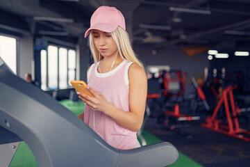 Side view of sporty blonde woman exercising on treadmill in gym