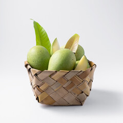 natural and raw or green mangos or aam in a basket with mango tree leaves on a white background for packaging or any editorial purpose.