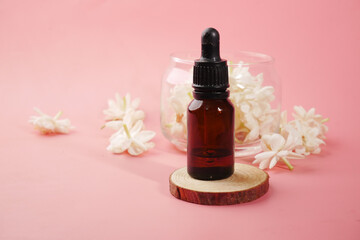 Fototapeta na wymiar eucalyptus essential oils in a glass bottle and flower on pink background 