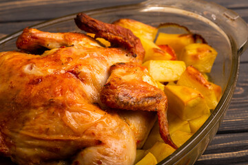 Grilled chicken with baked potato on a wooden table