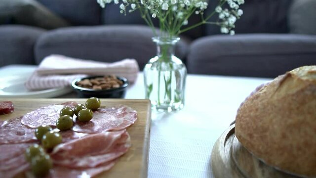 Slow motion looping footage of pan across delicious fresh food including bread, artisan charcuterie board, olives and nuts. Dinner party, picnic food concept filmed with natural back lighting