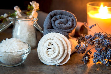 Beauty spa treatment and relax concept. Towel, sea salt and burning candle on a dark background