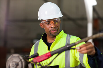 African American male engineer worker maintenance the automatic robotic machine in the factory....
