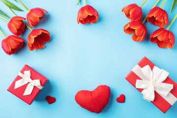 Mother's day background. Top view of gift with red tulip bouquet on blue table background