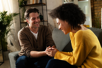 Young couple sitting and talking at home. Woman and man flirting and laughing
