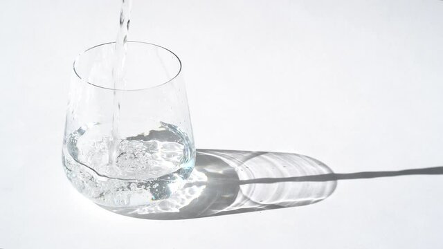 Crystal water is pouring from a jug into a glass. Glass of fresh pure water.