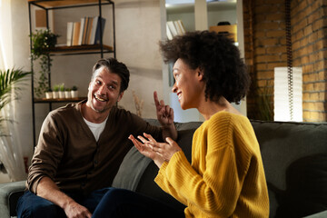 Young couple sitting and talking at home. Woman and man flirting and laughing