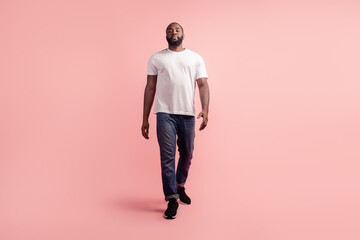 Portrait of young guy walk look camera on pink background