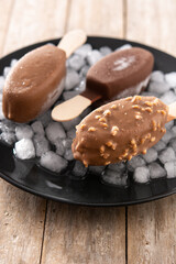 Chocolate popsicles and crushed ice on wooden table