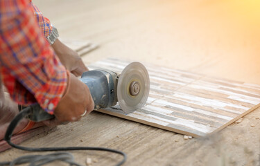 Fototapeta na wymiar Workman cutting ceramic tiles with handy machine
