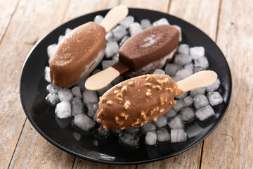 Chocolate popsicles and crushed ice on wooden table