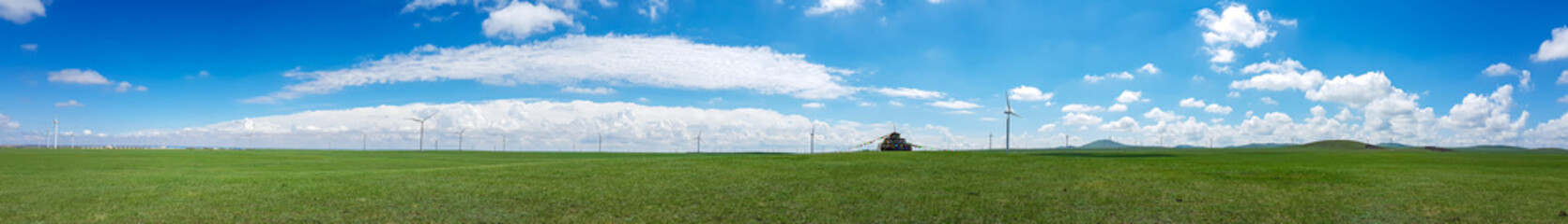 Obraz premium Heap of stones (Aobao) build on a vast pasture in Xilinhot in Inner Mongolia. The heap has a lot of colorful prayer flags attached to it. Endless grassland. Blue sky with white clouds. Religious place