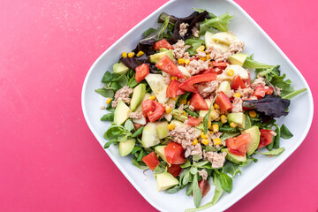 Ensalada de aguacate y verduras en plato sobre fondo rosa, comida vegetariana saludable y divertida