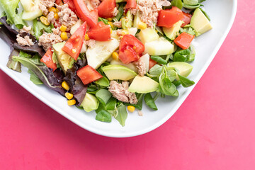 Ensalada de aguacate y verduras en plato sobre fondo rosa, comida vegetariana saludable y divertida