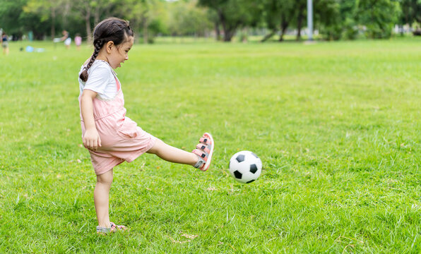 Sports kid. Happy little girl kid kicking a soccer ball, Child plays