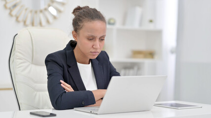 Pensive African Businesswoman Thinking and Working on Laptop in Office 