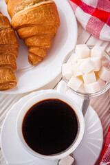 delicious fresh croissant and cup of coffee on a white wooden rustic background