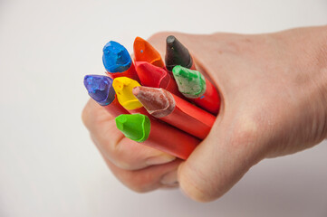 Female hand holding colorful oil pastel above white paper