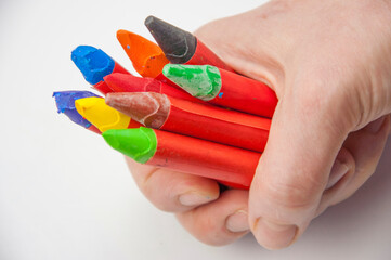 Female hand holding colorful oil pastel above white paper
