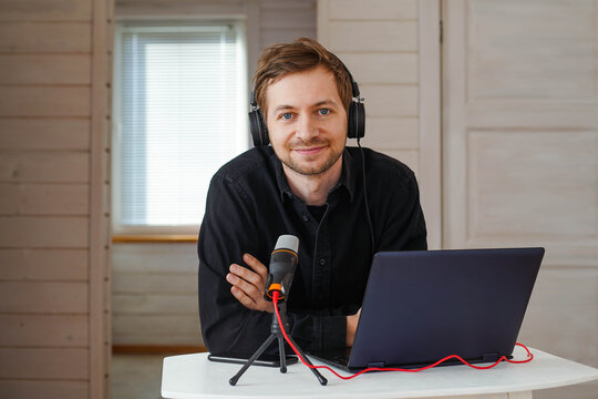 Portrait Of Influencer Podcast Creator Streaming Audio Broadcast At His Home. Broadcasting An Interview Using Microphone