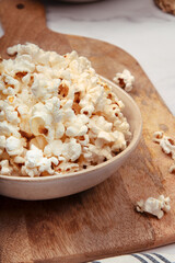 Ceramic bowl on a rustic wooden board with popcorn