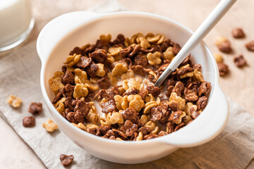 Tasty and healthy breakfast. Chocolate and vanilla cornflakes with milk in a white bowl close-up. Breakfast cereals.