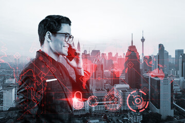 Fototapeta premium Eastern young handsome cybersecurity developer having conference call to protect clients confidential information by inventing solutions. IT lock icons over Kuala Lumpur city background.
