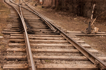 Fototapeta na wymiar Railway rails that run through grooved sleepers buried under cobblestones