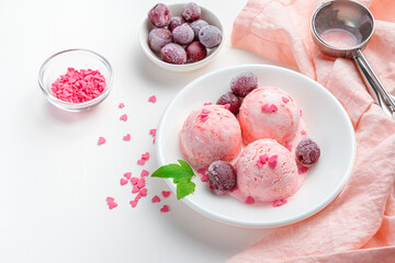 Cherry ice cream with frozen cherries on a white background with a pink napkin.
