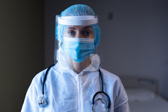 Caucasian Female Doctor In Hospital Wearing Ppe Suit, Face Mask, Face Shield And Medical Cap