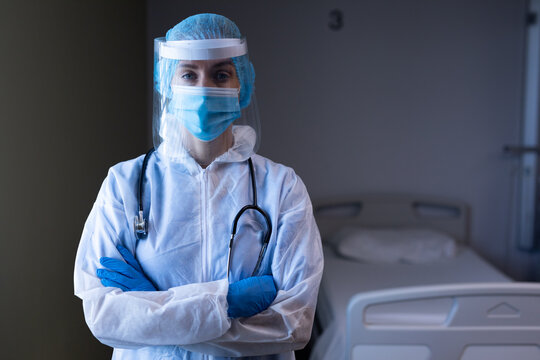 Caucasian female doctor in hospital wearing ppe suit, face mask, face shield and medical cap