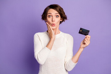 Photo portrait of amazed surprised girl with bank card touching cheek isolated on vivid purple...