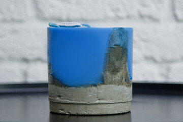 homemade blue candle with concrete on the background of a white wall. handmade decor close-up....