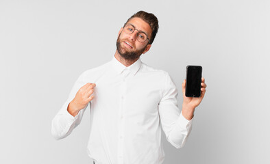 young handsome man looking arrogant, successful, positive and proud and holding a cell