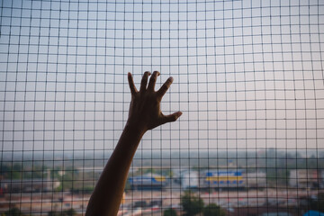 Man hand holding on chain link fence for freedom with dark feeling. concept of the freedom