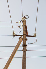 Electricity concept, concrete pole with high voltage wires on insulators. Close-up against the blue...