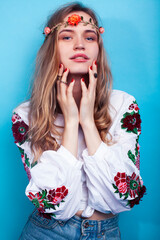 young pretty blond girl posing on blue background, fashion style hippie boho flowers on head