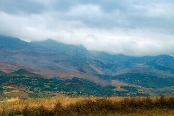 Moroccan landscape with foggy mountains and fields.