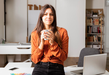 Woman working on laptop at office whit a cup of tea.