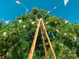Country fair decoration with wooden ladder and pennant flags for festival holiday against blue sky...