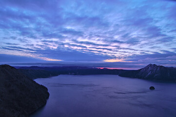薄い雲の広がる夜明けの湖。日本の北海道の摩周湖。