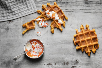 Traditional Belgian waffles on a baking silver tray with red caviar on grey clay background. Top...