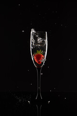 Strawberry falling in a glass with water on a black background
