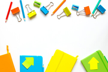 Back to school concept. bright notepads in yellow, orange, green and blue. Flat lay of school supplies: pencils, sharpener, bright