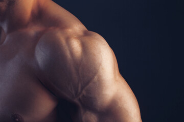Fitness man background shoulder biceps pectoral muscles triceps bodybuilder on a dark background...