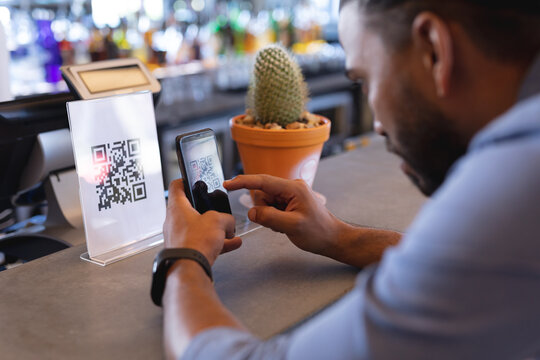Mixed race man using smartphone and reading qr code in cafe - Powered by Adobe