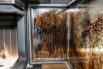 Cleaning the corner glass from soot in a modern fireplace with a closed combustion chamber standing...