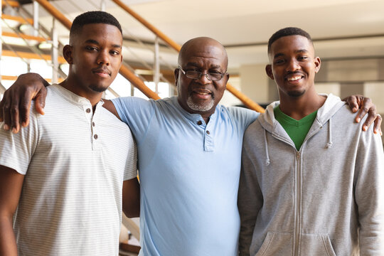 Portrait of african american senior man and his two sons smiling while standing at home