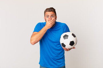 young handsome man covering mouth with hands with a shocked. soccer concept