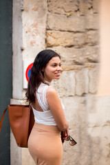 young woman smiling as she strolls through the streets of europe
